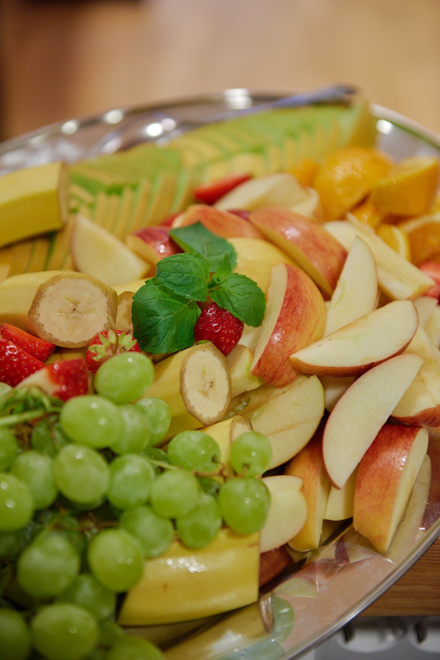 Un assortiment de fruits coupés en tranches, comprenant des pommes, des bananes, des raisins et des fraises.