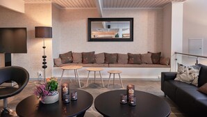 A modern living room with a sofa, two small tables, a black chair, and a floor lamp. - Slobrua Gjestegård (Sor-Odal)