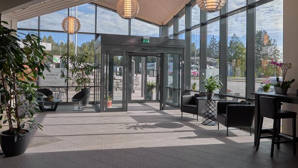 A spacious lobby with large windows, a revolving door, and modern furniture. - Slobrua Gjestegård (Sor-Odal)