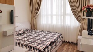 A bedroom with a bed, curtains, a bedside table, and a wall-mounted TV. - Florita SGN Green Living (Ho Chi Minh City)
