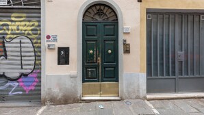 A green double door with a brass threshold, a metal grill over the door, and a small window above the door. - Santa Croce Retreat by MMega (Florence)