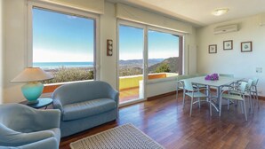 A room with a sofa, dining table, chairs, and large windows offering a view of the sea and hills. - 4 bedroom awesome home in Carrara -MS- (Carrara -MS-)