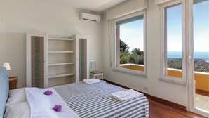 A bedroom with a bed, a chair, a wardrobe, and large windows with a view. - 4 bedroom awesome home in Carrara -MS- (Carrara -MS-)