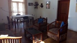 Una sala de estar con una mesa de comedor, sillas, un sofá, una mesa de centro y una puerta.