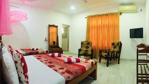 Habitación de hotel con dos camas, una silla, un escritorio, aire acondicionado y televisor.