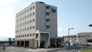 Ein modernes Hotel mit einem gut sichtbaren Rinnai-Logo, mehreren Etagen und einem Parkplatz vor dem Gebäude.