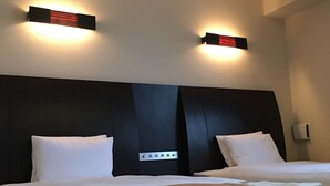 Ein Hotelzimmer mit zwei Betten, einem dunklen Kopfteil und zwei Wandleuchten.