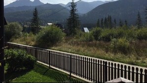 A view from a window overlooking a mountainous landscape with a wooden fence in the foreground.