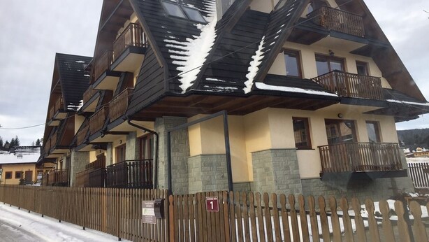 A chalet-style building with multiple balconies and a wooden fence.