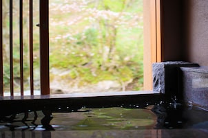 Vista a través de una ventana con baranda de madera, repisa de piedra y fuente de agua.