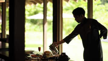 A person pouring a drink into a glass at a table with various dishes and a pitcher.