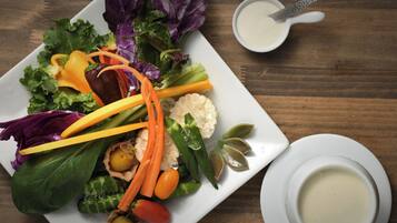 A white plate with a salad and a small bowl of dressing.