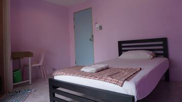 A bedroom with a bed, a chair, a small table, and a door.