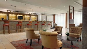 Um lobby moderno de hotel com área de bar, assentos e uma grande janela.