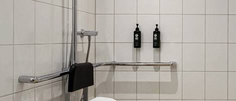 A shower with a glass door, a towel rack, and a shelf with toiletries.