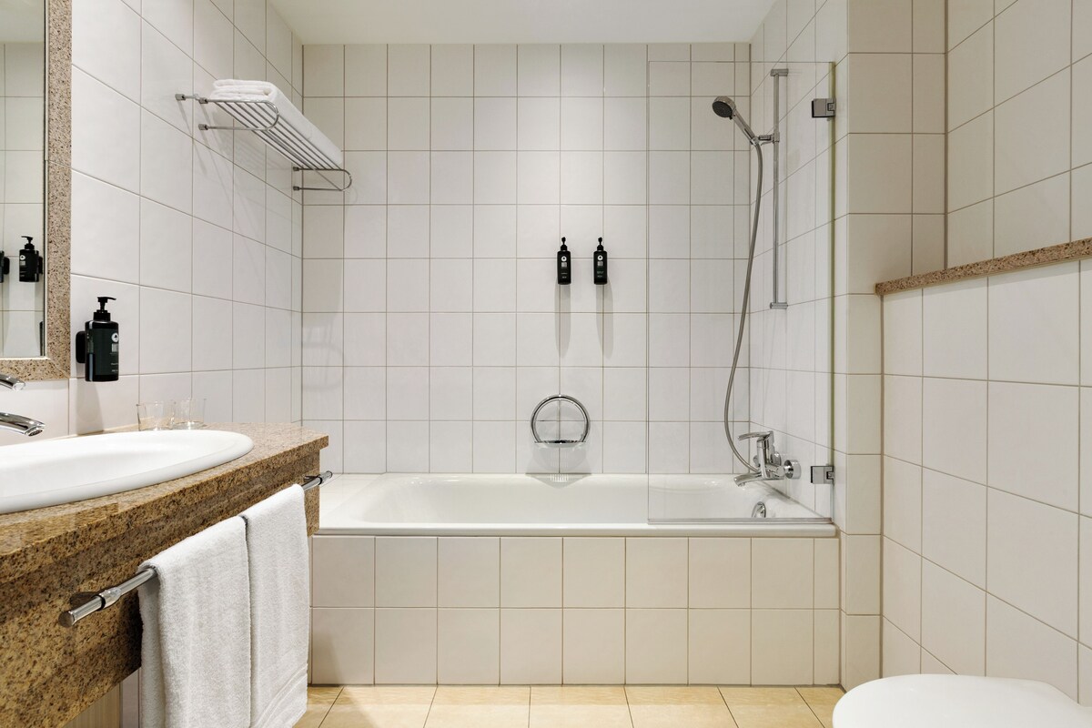 A modern bathroom with a bathtub, a shower, a sink, and a mirror.