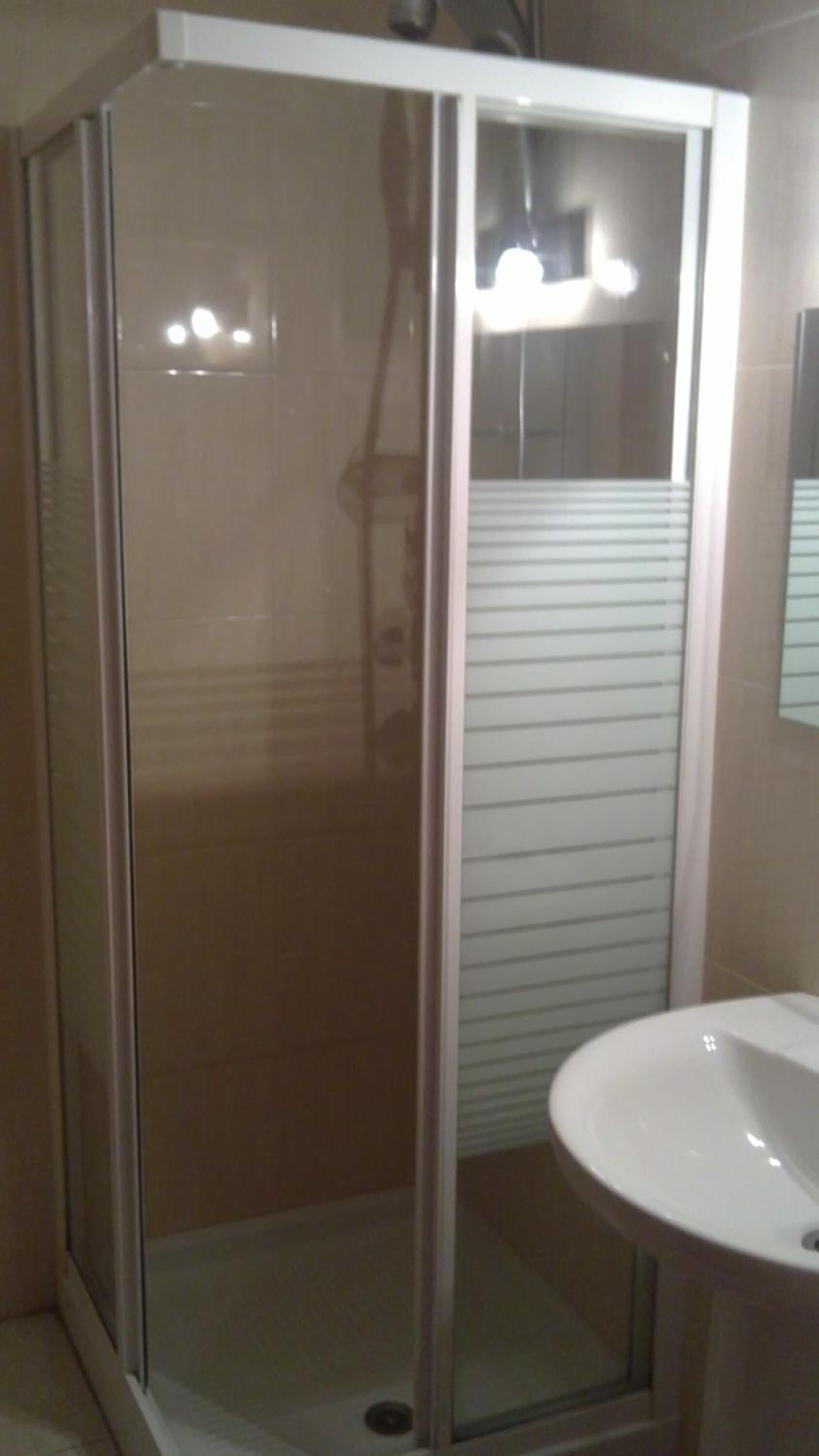 A glass-enclosed shower stall with a white sink to the right.