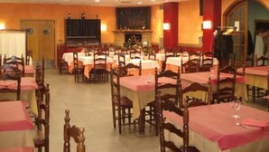 Ein Essbereich mit mehreren Tischen und Stühlen, eine Bar und ein Kamin.