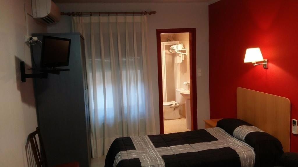 Une chambre d’hôtel avec un lit, une télévision, une douche et un mur d’accent de couleur rouge.