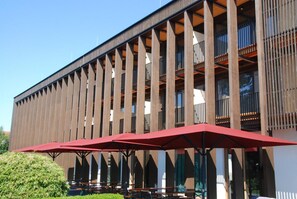 A modern building with a series of balconies and outdoor seating areas with red umbrellas. - Gasthof-Hotel Hoehensteiger (Rosenheim)