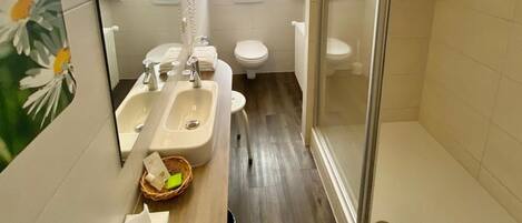 A compact bathroom with a sink, toilet, and shower.