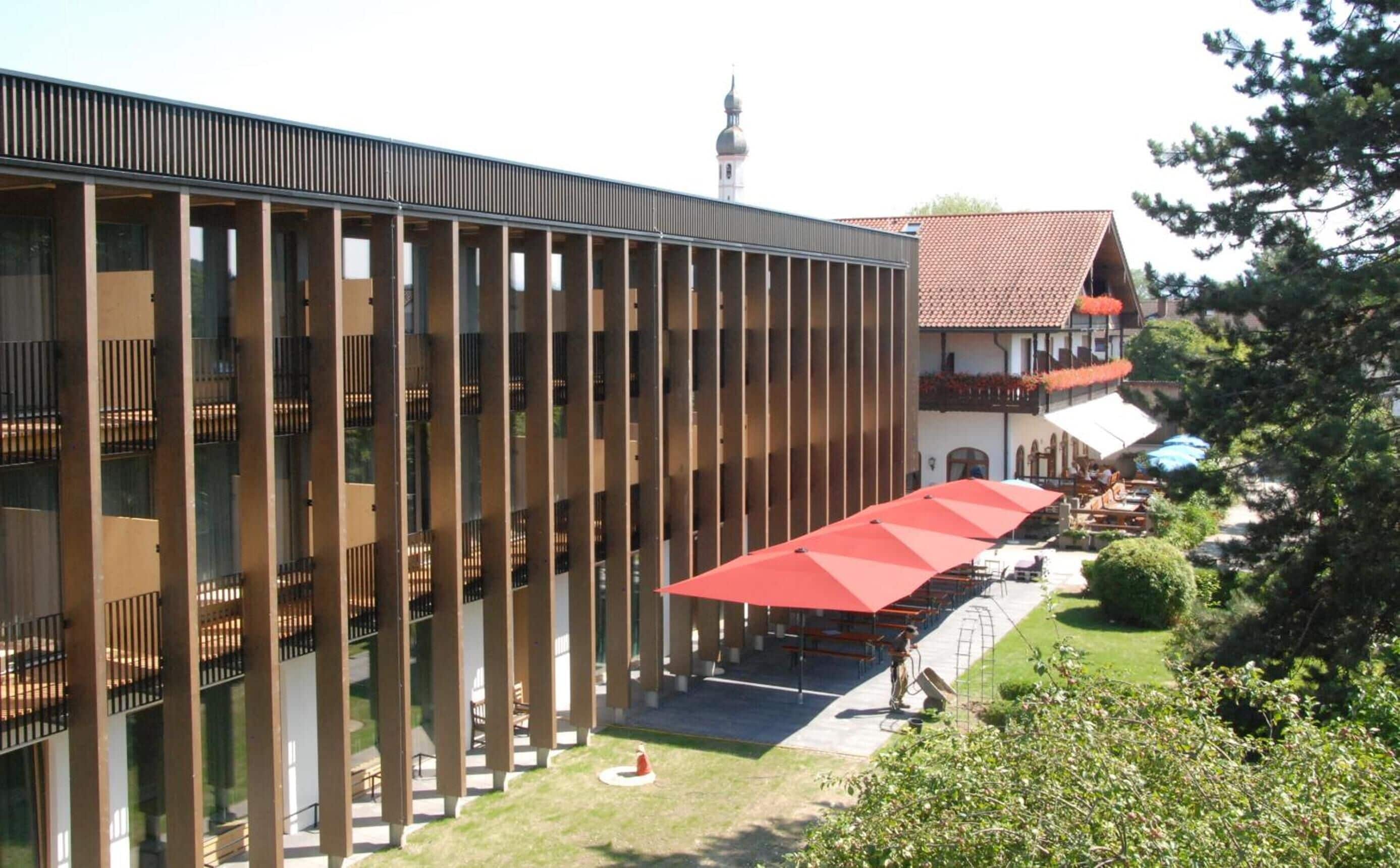 Un edificio moderno con fachada de vidrio y un patio con mesas al aire libre.