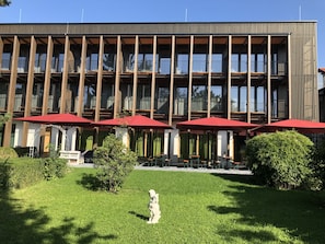 A modern building with a row of balconies and red umbrellas. - Gasthof-Hotel Hoehensteiger (Rosenheim)