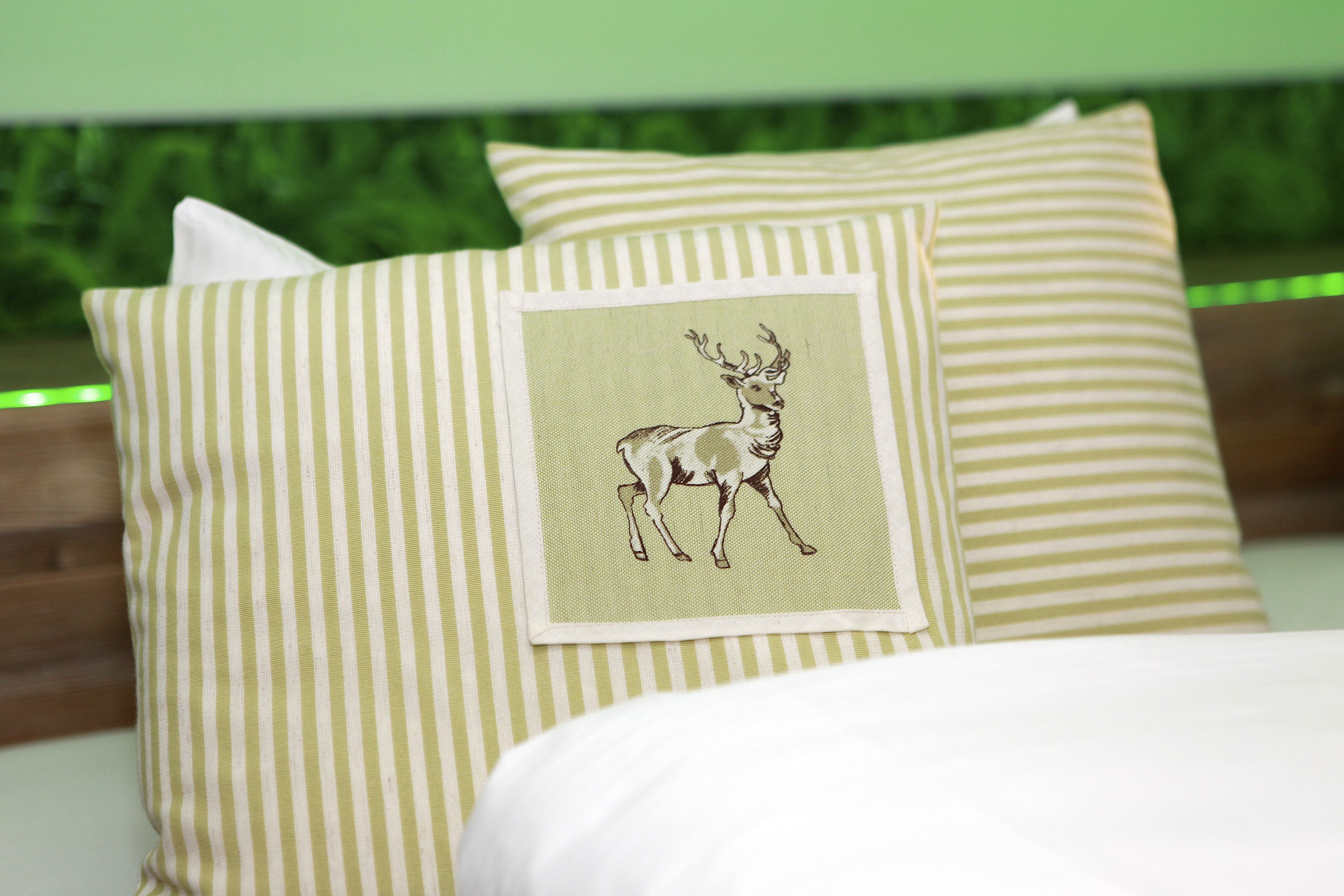 A bed with striped pillows and a pillow with a deer illustration.