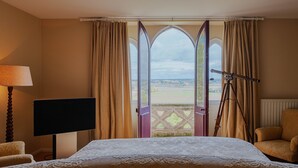 A bedroom with a large bed, a television, a tripod, and a chair.