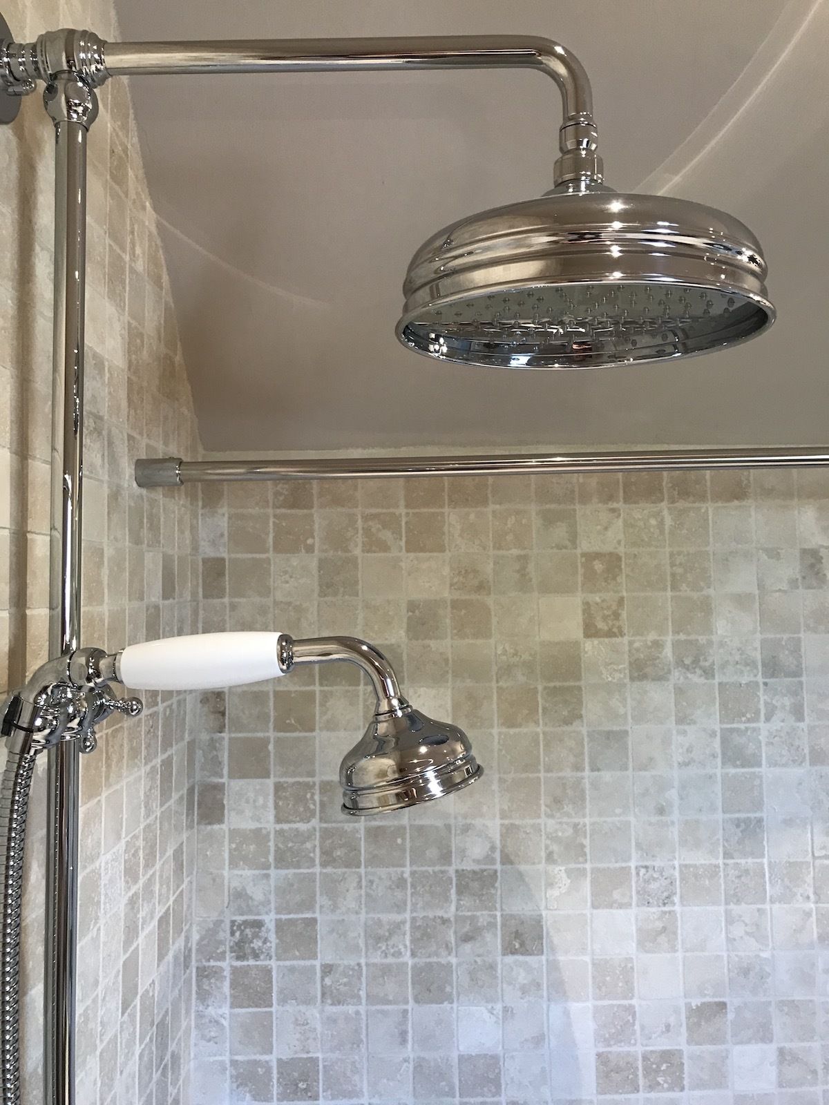A shower with a chrome head and a handheld showerhead.