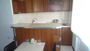 A kitchen with wooden cabinets, a white countertop, and a table with chairs. - Apartments Tigran Petrosyan (Yerevan)