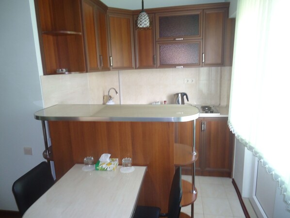 Una cocina con armarios de madera, encimera blanca y una mesa con sillas.