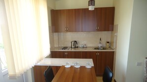 A compact kitchen with wooden cabinets, a sink, and a dining area with two chairs and a table. - Apartments Tigran Petrosyan (Yerevan)