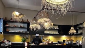 Una cocina moderna con lámparas colgantes, una mesa de buffet y un chef preparando comida.