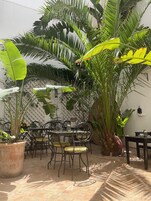 Un espacio al aire libre con mesa y sillas, rodeado de exuberantes plantas tropicales.