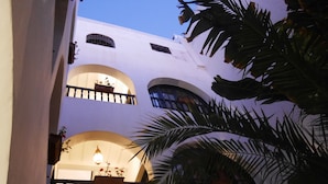 Un edificio de varios pisos con balcones, ventanas arqueadas y plantas en macetas.