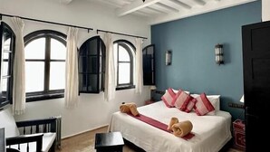 Una habitación con una cama, un escritorio, una silla y dos ventanas con cortinas.
