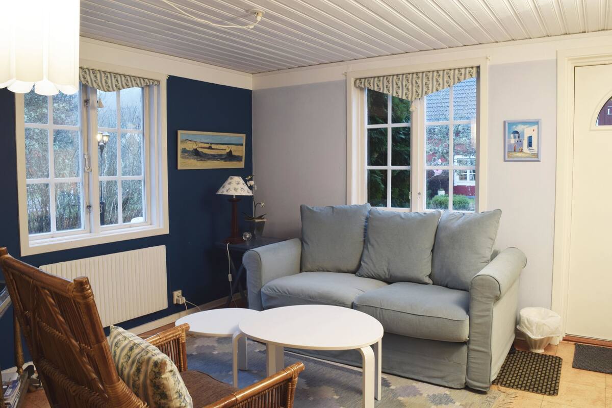 A cozy living room with a grey sofa, two white side tables, a wooden chair, and a lamp.