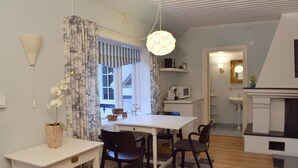 Cocina compacta con cubierta blanca, microondas y pileta. Hay un comedor con mesa blanca y sillas negras.