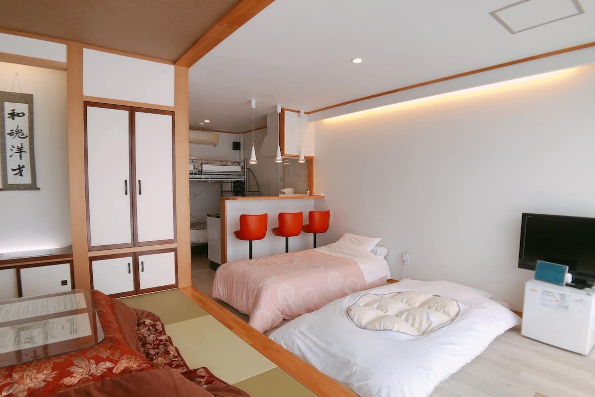 A hotel room with a bed, a desk, a chair, a TV, and a wardrobe.