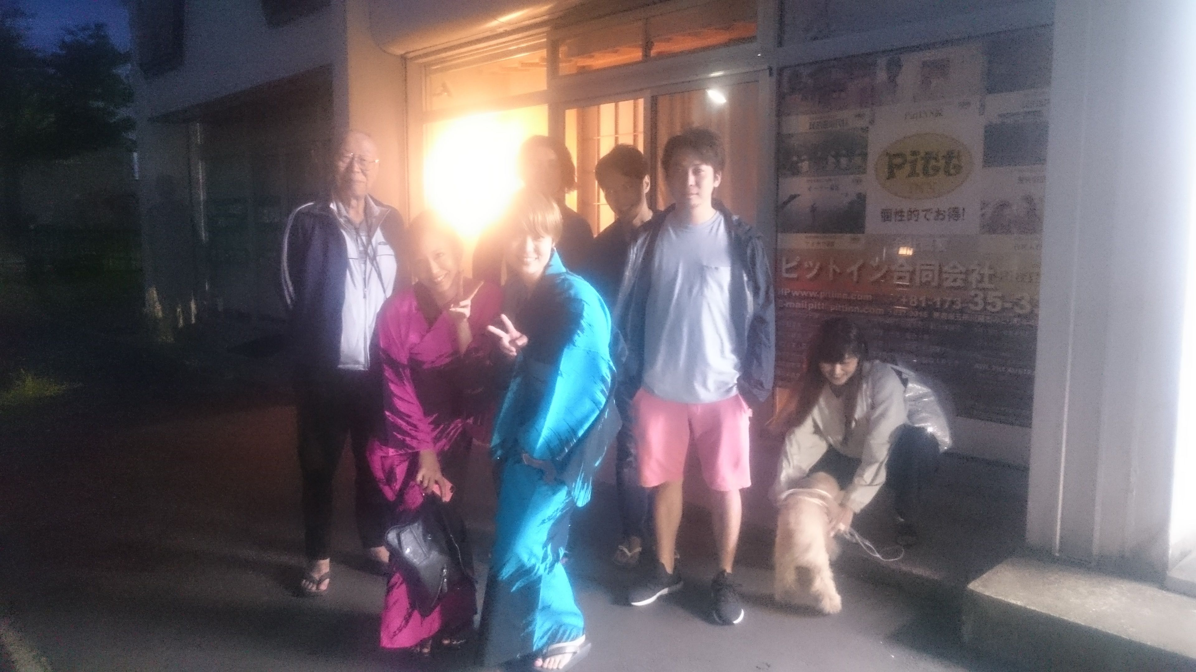 A group of people outside a building with a signboard.