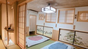Una habitación japonesa tradicional con suelo de tatami, dos futones de tatami, biombos shoji y obras de arte en las paredes.