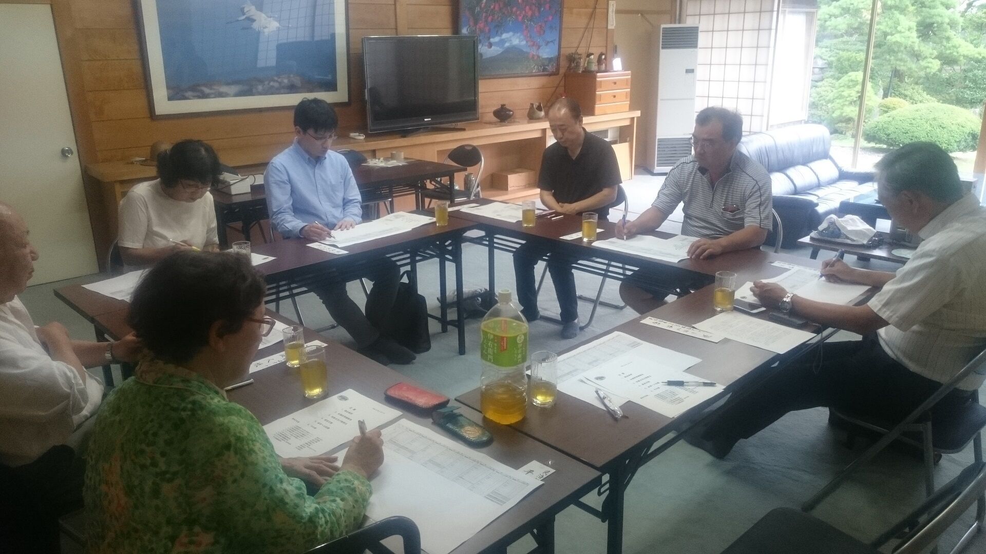 A conference room with a long table, chairs, papers, and a television.