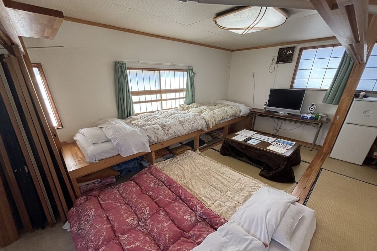A room with a bunk bed, a desk with a computer, and a small kitchenette.