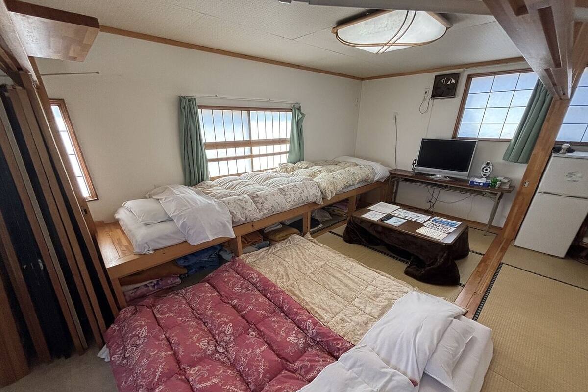 Une chambre avec un lit superposé, un bureau avec un ordinateur et une petite kitchenette.