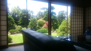 Una habitación con un ventanal amplio que ofrece vistas a un jardín con diversos árboles y arbustos.