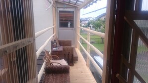 Un balcón con mobiliario de mimbre y una mesita, con vistas a una zona residencial.