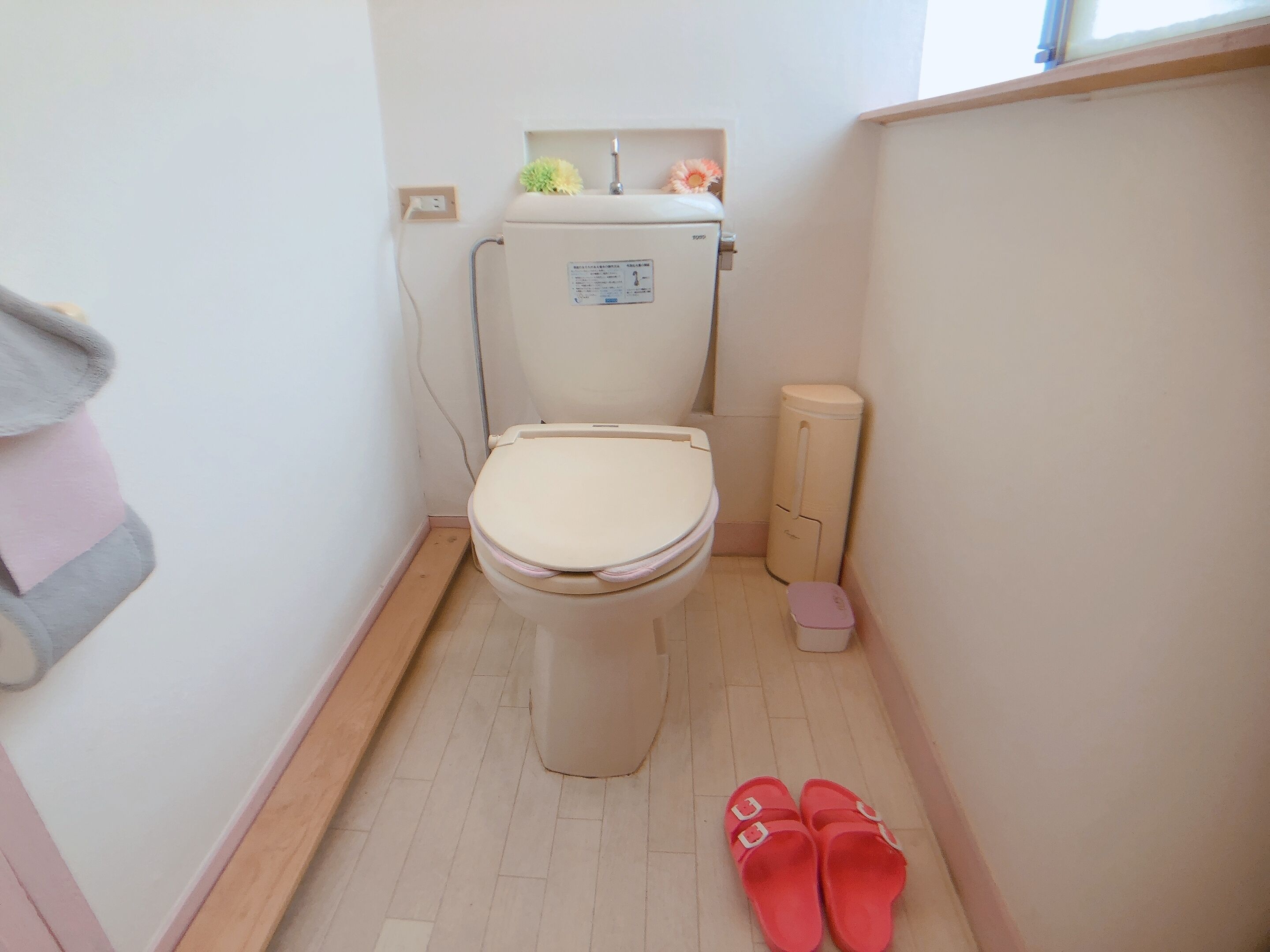 A small bathroom with a toilet, a sink, and a trash bin.