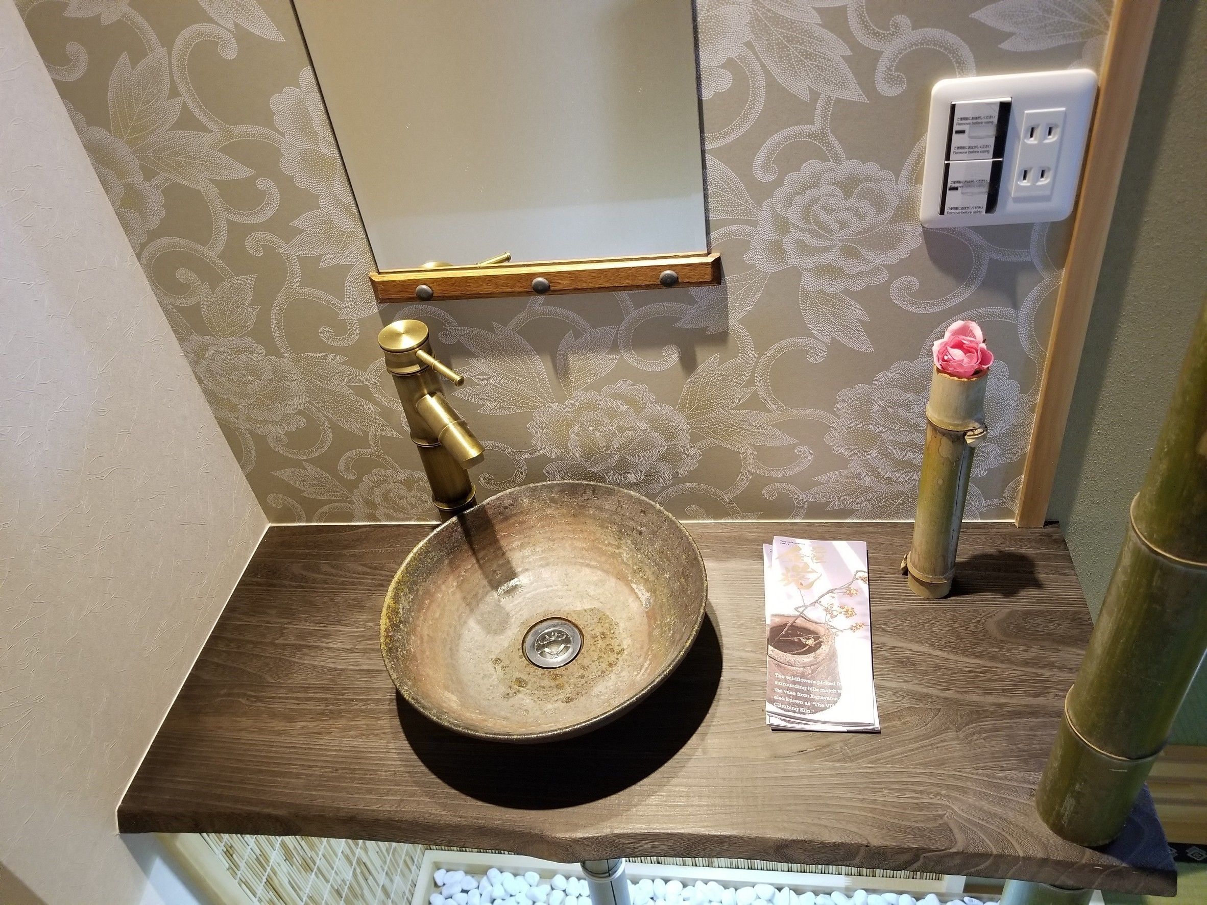 Een badkamer met een houten wastafelmeubel, een rond wastafel en een spiegel erboven.