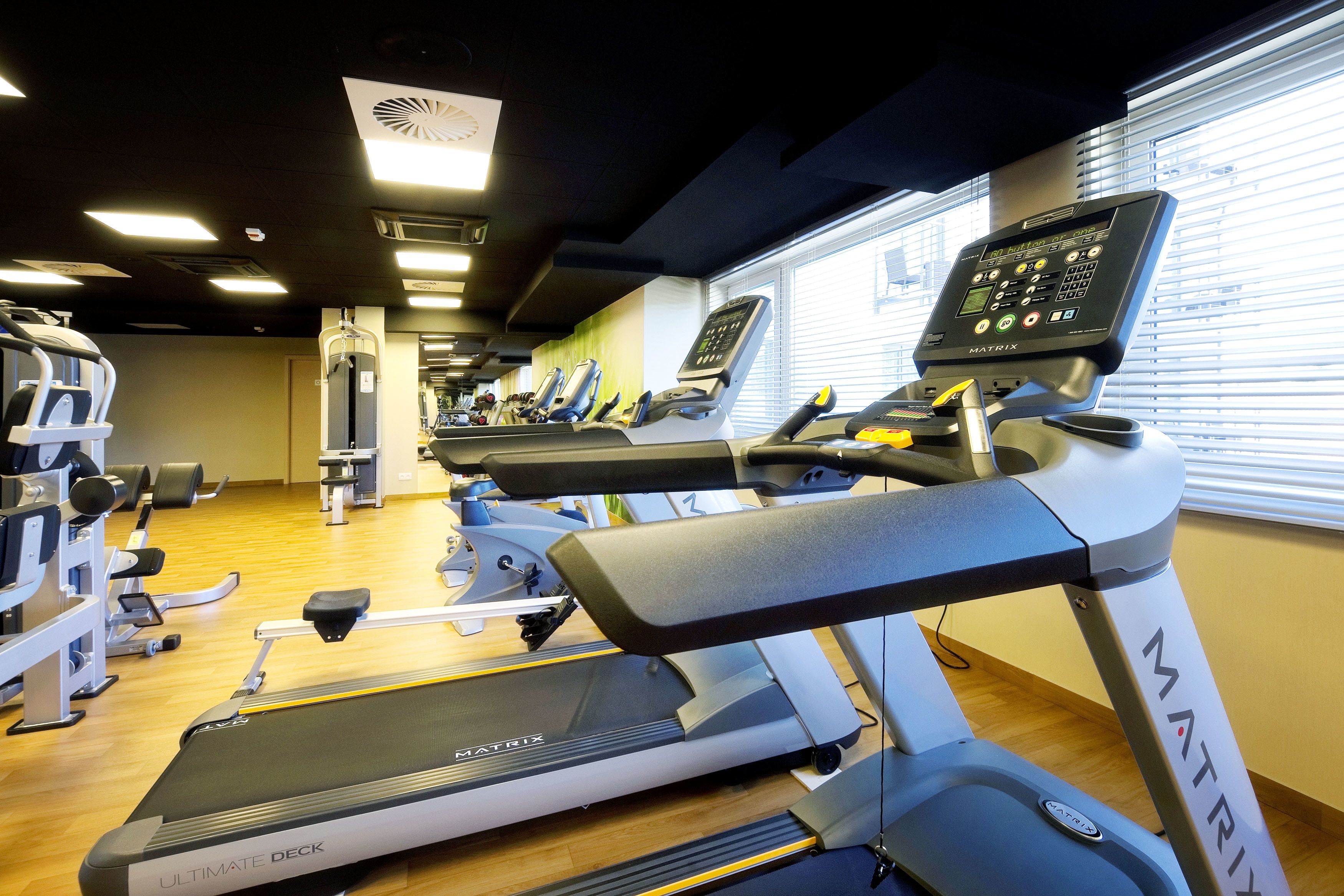 Un gimnasio con cintas de correr, máquinas de pesas y un espejo.